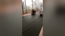 Skilful Chinese rider avoids parked cars as his three-wheeler slides down slippery road
