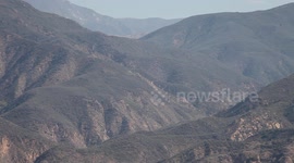 Fire helicopters approach through rugged terrain (Castaic Warm Fire) V18936