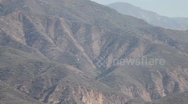 Fire helicopter (distant) flying through rugged terrain (Castaic Warm Fire) V18942