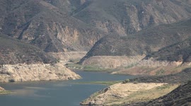 Fire helicopter approaches low lake level through rugged terrain (Castaic Warm Fire) V18953
