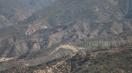 Fire helicopter (distant) flying away through rugged terrain (Castaic Warm Fire) V18956