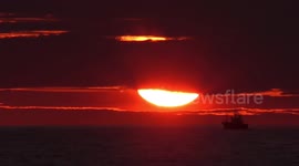 Espectacular puesta de sol. Un barco pesquero cruza por delante del sol cuando este se esta poniendo en el horizonte