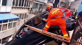 Firefighters rescue passengers trapped in car dangling over wall in China