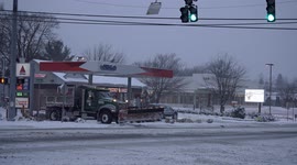 Post Road in Norwalk, Connecticut during  Winter Storm Kenan and windy conditions with snow plow truck leaving from gas station