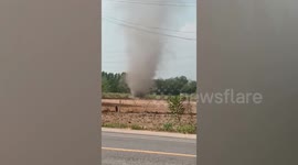 Powerful dust devil tornado tears through fields next to busy road in Thailand