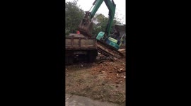 Excavator operator expertly moves vehicle onto back of truck