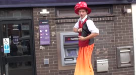 Very Tall stilted man    dressed as clown  using ATM As you do  in Sherringham UK  2011