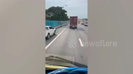 Loose car wheel rolls along busy highway in Thailand