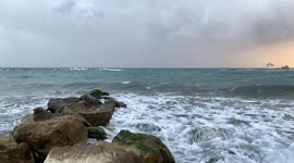 Storm sea. Cyprus view from the coast in cloudy weather. On the horizon is a passenger liner.