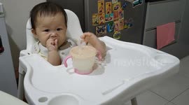 Adorable baby girl sitting like a boss while eating biscuit