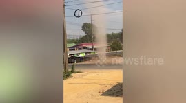 Dust devil tornado swirls next to road before engulfing onlookers in Thailand