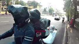 Pet dog enjoys scenery from boat-like compartment attached to moving motorbike