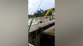 Backhoe stuck next to floodgate after being swept by flash flood in western Thailand