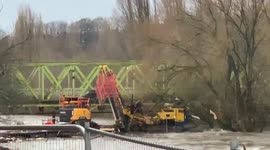 Huge digger floats down flooded river, smashing into bridge, during UK storm