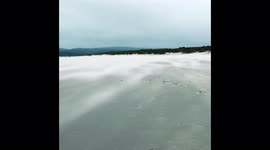 Walker blasted with sand on beach in southwest England's Dorset during Storm Franklin