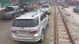 Train has a tight squeeze through cars parked next to tracks