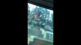 Ukrainians throw food parcel to soldier on a tank as they drive alongside