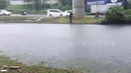 Motorcycle riders struggle to pass through flooded road in Malaysia
