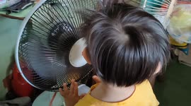 Adorable toddler sings in front of a table fan