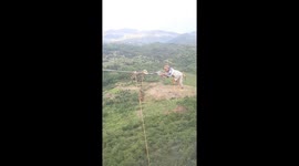 Electricians swing on high-voltage wires hundreds of metres above the ground in Vietnam