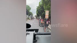 Bread vendor balances stack of plastic containers on his head
