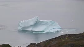 Big iceberg capsizes in front of greenlandic village