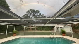 A beautiful Rainbow fills the sky behind the pool at a villa in Miami, Florida!!