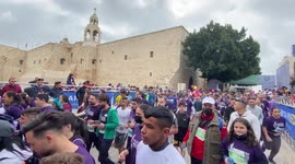 Runners pass by the Israeli separation barrier during the Palestine eighth international Marathon