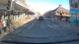 dashcam video  Electric scooter dangerously riding out of shop onto rd and riding through a red light on pedestrian crossing