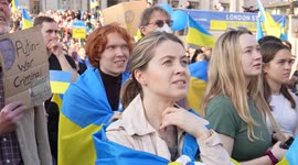 Light haired woman standing in a crowd, watching the London Stands with Ukraine: March and Vigil stage