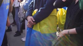Mans hands crossed with Ukraine flag around waist at the London Stands with Ukraine: March and Vigil