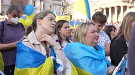 Woman with Ukraine flag on her back at the London Stands with Ukraine: March and Vigil listening and watching different view