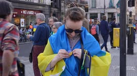 Woman putting Ukraine pin on herself at the London Stands with Ukraine: March and Vigil