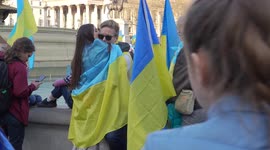 Couple hugging with Ukraine flag on their back at the London Stands with Ukraine: March and Vigil