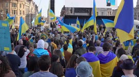 People waving Ukraine flags from the back at the London Stands with Ukraine: March and Vigil