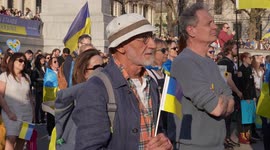 Man with hat holding a Ukraine flag at the London Stands with Ukraine: March and Vigil