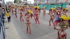 Stream of carnival performers dressed in vibrant outfits pass through Colombian city