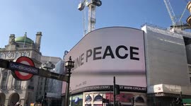 Ukrainian Crisis March in London at Eros statue while Picadilly Circus shows the words”Imagine Peace”