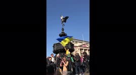 Woman waving Ukrainian flag in Piccadilly Circus at the Eros statue during the Ukrainian Crisis March