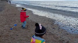 Two kids throwing stones into the sea at Saltburn Beach in North Yorkshire, UK