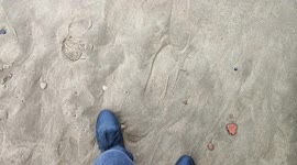 Man walking with black shoes on a beach with footprints Whitby North Yorkshire