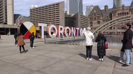 Tourists checking out Toronto city hall and taking pictures as travel and tourism season resumes and COVID-19 pandemic restrictions are lifted for now