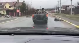 Car drives past corpses in Bucha, Ukraine