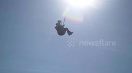 Two Paragliders use a cliff jump to launch in to Spring sunshine and good wind conditions at Fistral beach Newquay Cornwall.