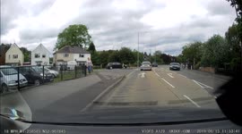 A teenager on a cycle pull a wheelie while crossing in front of the cam car.