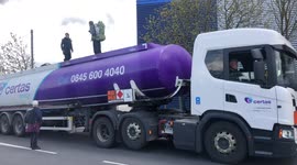 Climate activists climb onto fuel tanker and block traffic at oil depot near Heathrow Airport