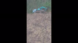 The truck driver transporting an excavator crosses a narrow road on a cliff hundreds of meters high