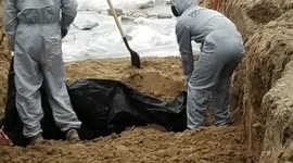 GRAPHIC: Workers remove bodies from second mass grave in Bucha a day after Biden said Putin was committing 'genocide'