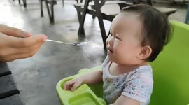 Adorable baby shows tongue-play when mom feeding her with ice cream