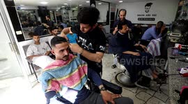 Palestinians sit for a haircut at a hairdresser as Muslims prepare to celebrate Eid al-Fitr